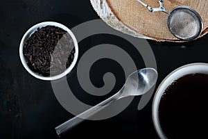 Overhead shot of a teacup and a bowl of fresh tea leaves