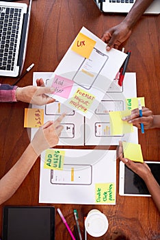 Overhead shot of team working together on mobile app layout design, UX