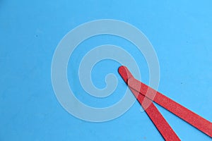 Overhead shot of two red nail files on blue background with space for your text