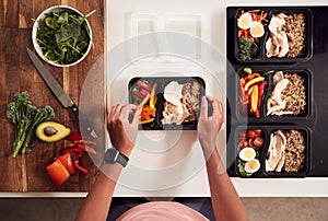 Overhead Shot Of Woman Preparing Batch Of Healthy Meals At Home In Kitchen