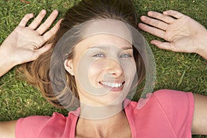 Overhead Of Smiling Woman Lying On Grass