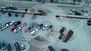 overhead tilt aerial footage of parked cars, people walking, cars driving on the street, retail stores, restaurants, boats