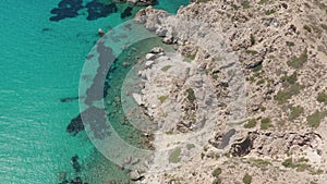 Overhead Top Down Aerial Flight over Greek Island Mykonos Turquoise Blue Ocean with Rocky Cliff Coast