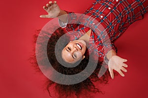 Overhead top view of cheerful young african american girl in pajamas homewear posing resting at home  on red