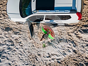 overhead top view happy woman getting out from the car in flippers with inflatable ring and bag