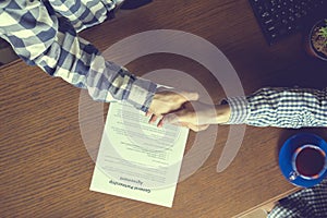 Overhead top view of two workers in casual in the office signing the contract agreement on table