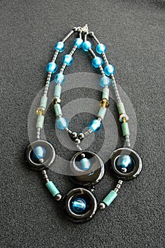 Overhead vertical shot of a neckless on a black surface