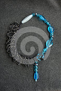 Overhead vertical shot of a neckless on a black surface