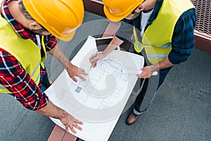 overhead view of architects in safety vests and helmets drawing