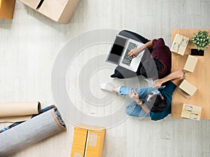 Overhead view of Asian young e-commerce seller small business use laptop device for tracking delivery shipping order and packing