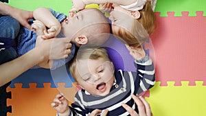 Overhead view of babies lying on mat at nursery playgroup being tickled
