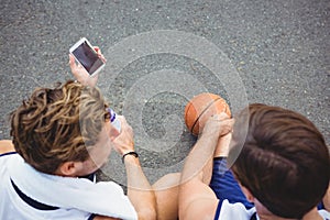 Overhead view of basketball player showing mobile phone to friend