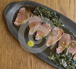 Overhead view of bonito sashimi fillets with wasabi sauce and seaweed photo