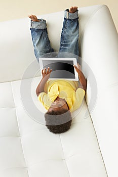 Overhead View Of Boy On Sofa Playing With Digital Tablet