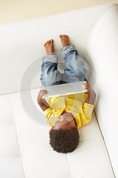 Overhead View Of Boy On Sofa Playing With Digital Tablet