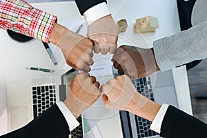 Overhead view of business people putting hands fist join together over meeting desk, partnership colleagues holding hands as
