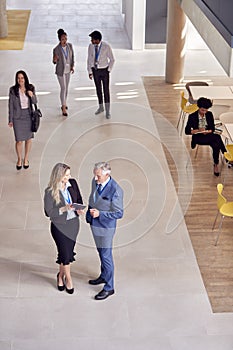 Overhead View Of Businesspeople Meeting In Lobby Of Busy Modern Office Building