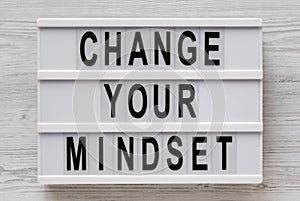 Overhead view, `Change your mindset` words on a lightbox on a white wooden background. From above, flat lay, top view