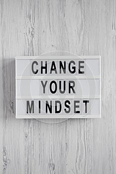 Overhead view, `Change your mindset` words on a lightbox on a white wooden background. Top view, from above, flat lay