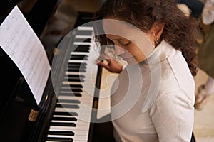 Overhead view of a charming brunette female pianist, musician performing classic melody on pianoforte