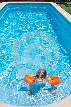 Overhead view of child with armbands in pool