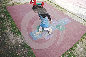 Overhead view child girl playing hopscotch on the school playground. Popular street children's games in classics