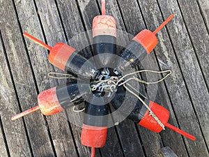 An overhead view of a circle of red and black lobster buoys tied together with rope on a dock in Maine, USA