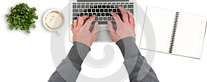 overhead view of clean white office desk with person typing on laptop computer