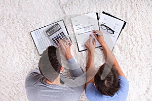 Overhead View Of Couple Calculating Invoice