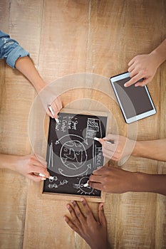 Overhead view of cropped hands writing business terms on slate with person using digital tablet