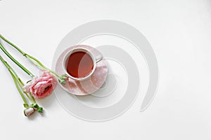 Overhead view of cup of tea and pink flowers isolated on white background. Flat lay, romantic female morning.