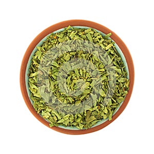 Overhead view of cut tarragon in a small terracotta bowl