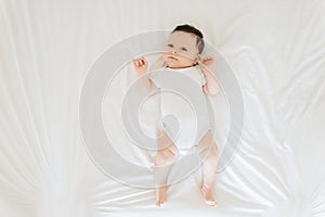 overhead view of cute newborn baby in white bodysuit lying
