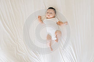 overhead view of cute newborn baby in white bodysuit lying photo