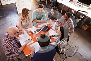 Overhead View Of Designers Having Meeting Around Table