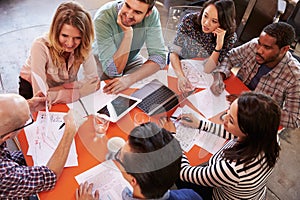 Overhead View Of Designers Having Meeting Around Table