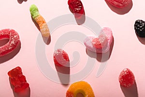 Overhead view of differently shaped colorful sugar candies on pink background