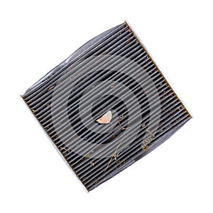 Overhead view of a dirty cabin air filter at an angle with dried leaves and dirt isolated on a white background