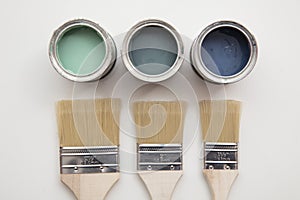 Overhead view of a DIY paint brush with green and blue sample paint pots