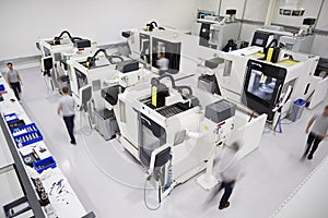 Overhead View Of Engineering Workshop With Workers Using CNC Mac