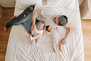 overhead view of father lying on bed together with little sons