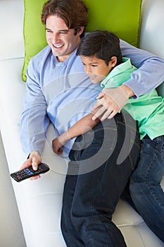 Overhead View Of Father And Son Relaxing On Sofa Watching TV