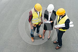overhead view of female architect and male workers in hardhats working with clipboard