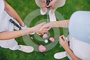 overhead view of female golf players with golf clubs shaking hands while standing