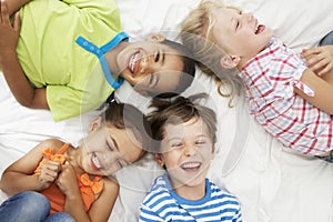 Overhead View Of Four Children Playing On Bed Together
