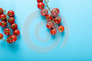 Overhead view of fresh red cherry tomatoes twigs on blue background with copy space