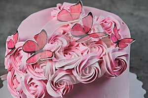 Overhead view of a freshly baked cake decorated with pink icing sugar roses displayed on a cake stand over a black