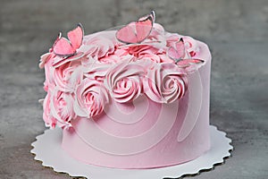 Overhead view of a freshly baked cake decorated with pink icing sugar roses displayed on a cake stand over a black