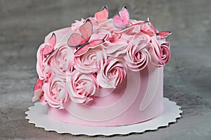 Overhead view of a freshly baked cake decorated with pink icing sugar roses displayed on a cake stand over a black