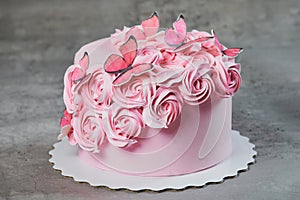 Overhead view of a freshly baked cake decorated with pink icing sugar roses displayed on a cake stand over a black